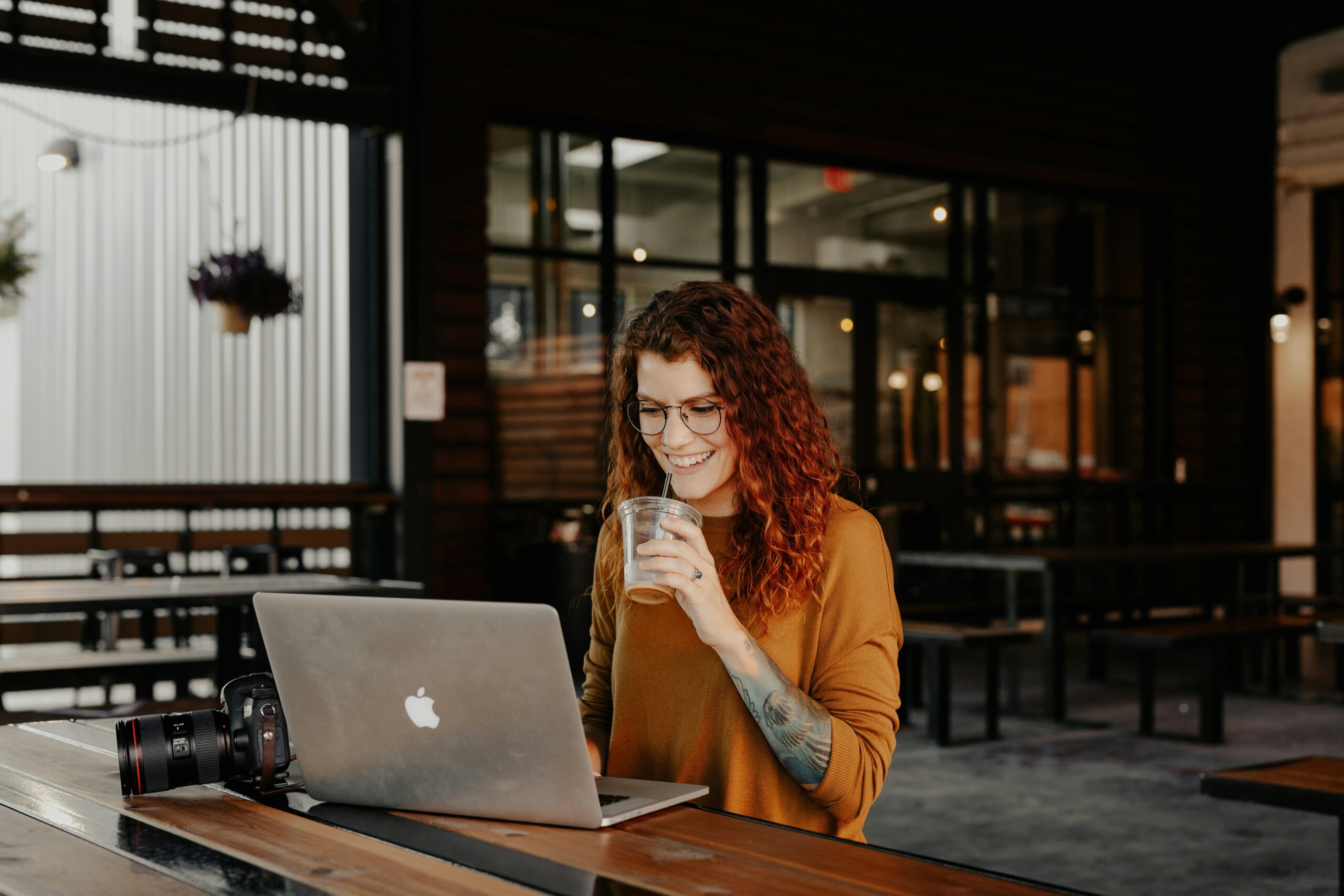 Woman smiling while writing notes in a notebook near her laptop