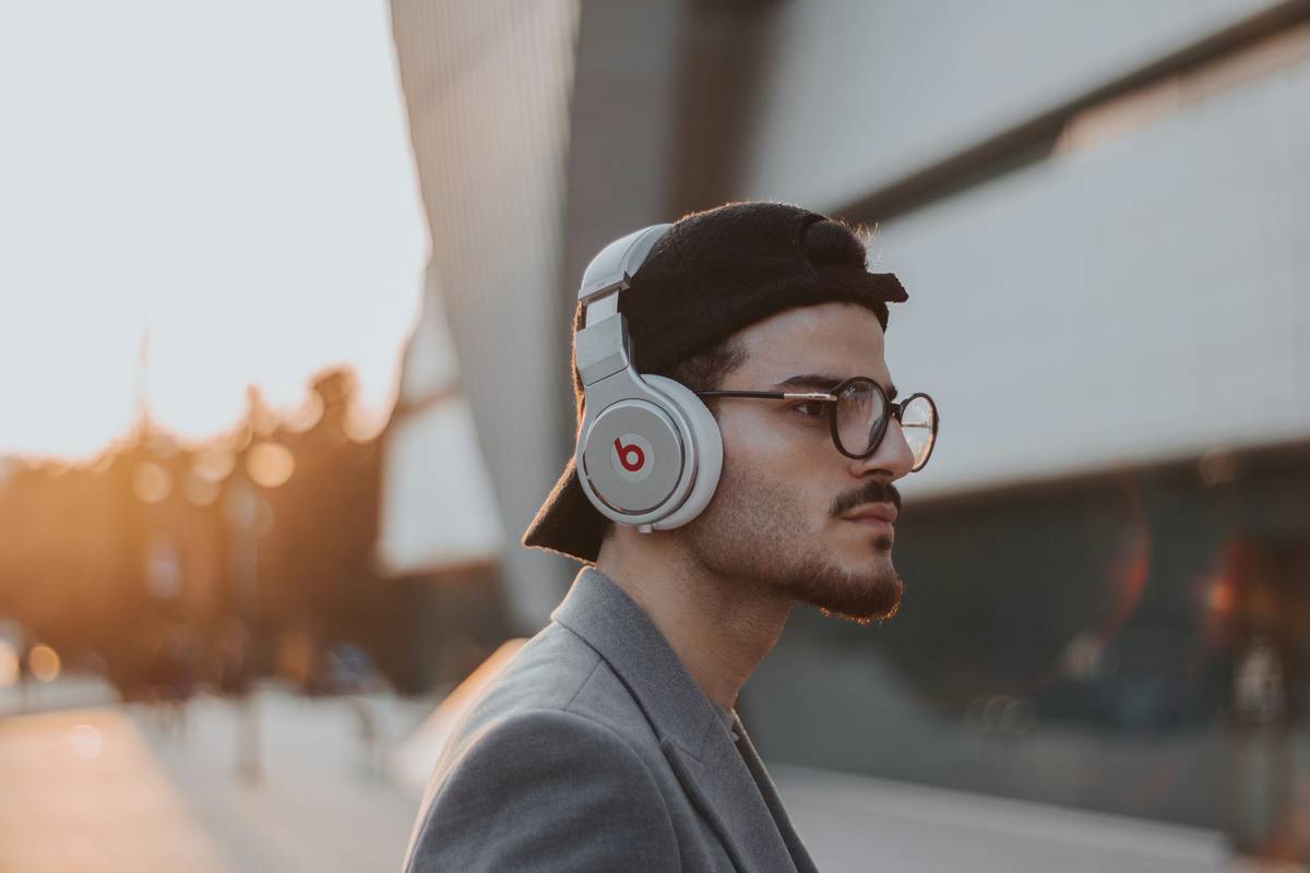 A photo of someone wearing peaceful earbuds while reading outdoors.