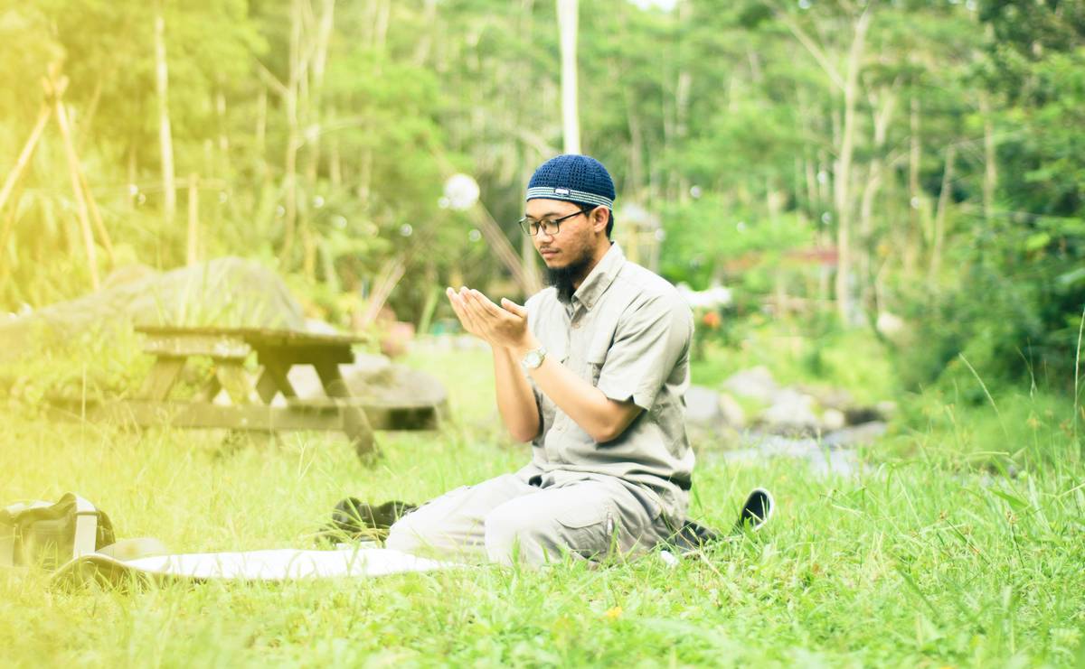 A person sitting cross-legged on a yoga mat practicing mindful breathing outdoors.